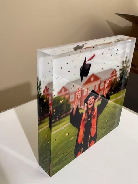 A decorative graduation-themed gift box featuring images of graduates in caps and gowns with academic buildings and celebratory elements